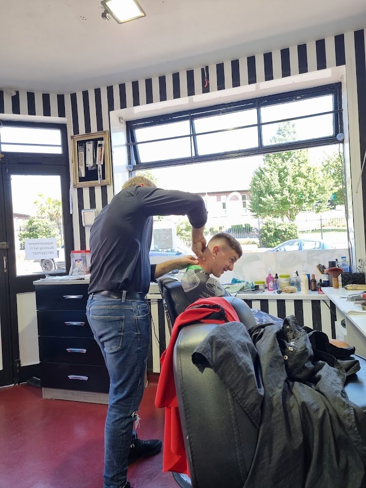 Barber at work inside Ballinlough Barbershop, Turners Cross, with the booking number on the door